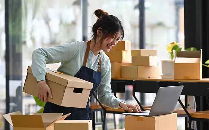Frau Kennzeichnet Pakete und verpackt sie Frau Kennzeichnet Pakete und verpackt sie