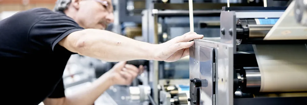 Mann der an Druckmaschine für Etiketten steht  Mann der an Druckmaschine für Etiketten steht