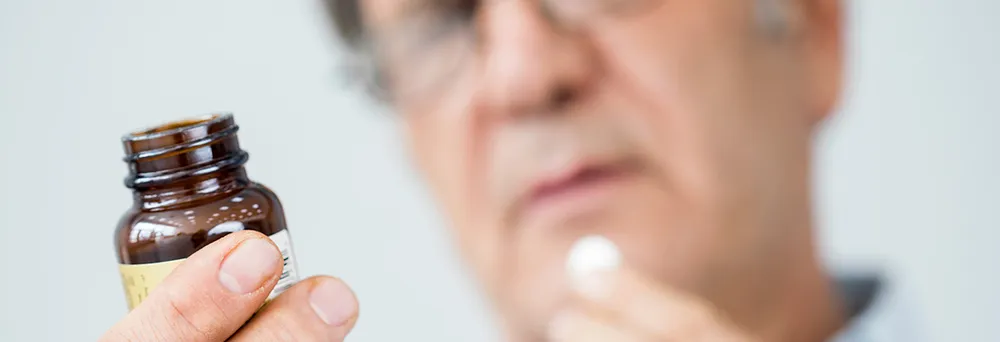 Mann liest Rückseite eines Medikaments