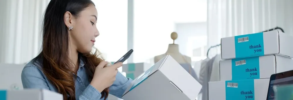 Frau scannt QR Code an Paketen Frau scannt QR Code an Paketen