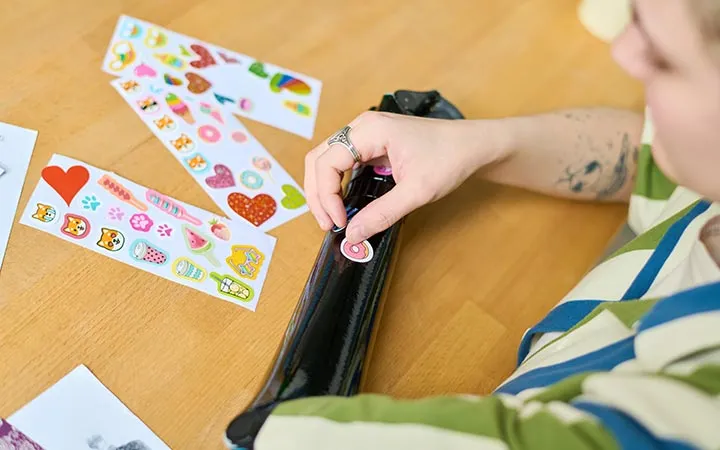 Frau klebt bunte Etiketten auf Armprothese Frau klebt bunte Etiketten auf Armprothese