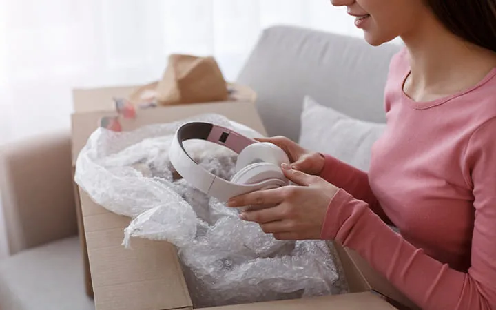 Frau packt Kopfhörer aus Versandkarton aus  Frau packt Kopfhörer aus Versandkarton aus