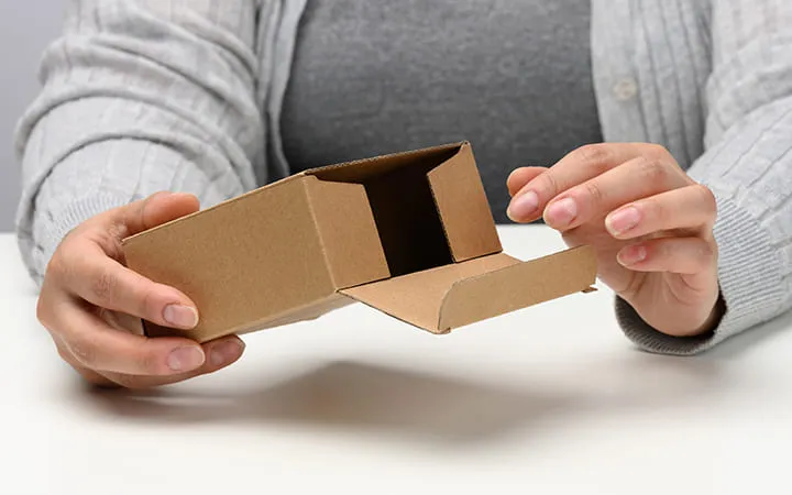 Frau hält Faltschachtel mit Einstecklasche Frau hält Faltschachtel mit Einstecklasche