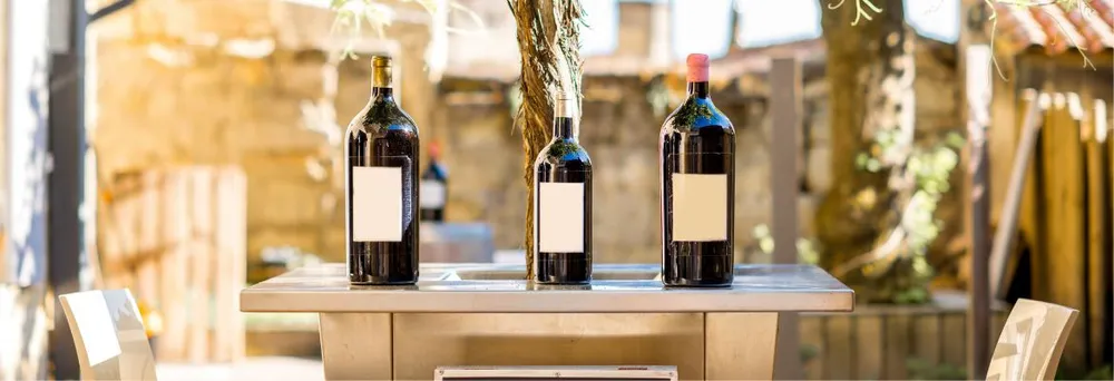 Weinflaschen mit weissen Etiketten auf Tisch Weinflaschen mit weissen Etiketten auf Tisch
