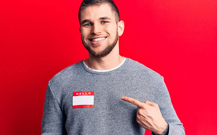 Mann deutet auf Namensetikett auf seiner Brust Mann deutet auf Namensetikett auf seiner Brust