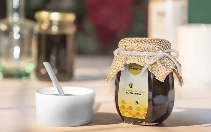 Honigglas mit passendem Lebensmitteletikett und einer kleinen Schlüssel nebendran mit Honig  Honigglas mit passendem Lebensmitteletikett und einer kleinen Schlüssel nebendran mit Honig