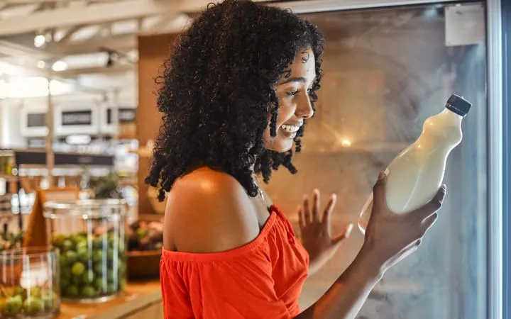 Frau liest Etikett auf Milchflasche Frau liest Etikett auf Milchflasche